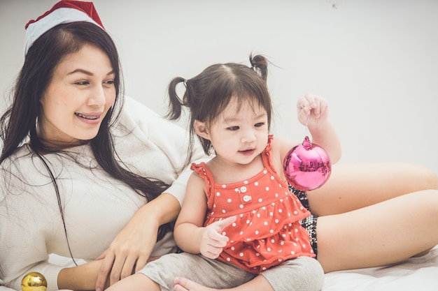 Madre feliz y bebé de la familia que juegan a casa el días de fiesta de la Navidad.