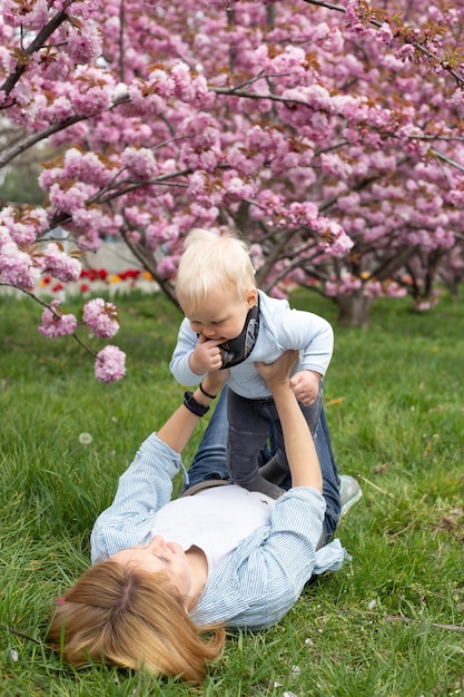 Madre feliz con una camisa azul jugando con un hijo en primavera Maternidad y feminidad