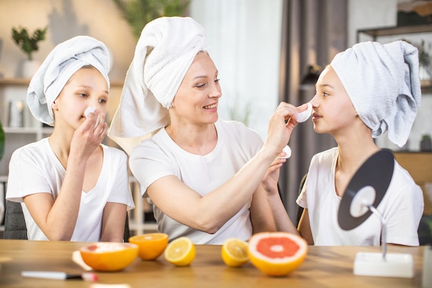 Madre feliz enseñando a sus hijas a cuidar la piel