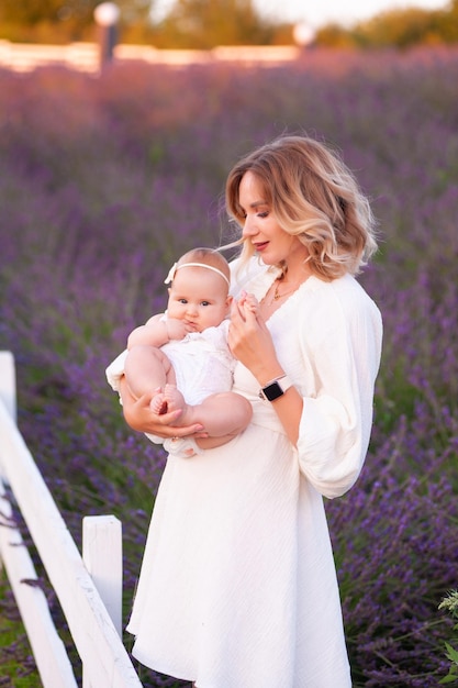 Madre feliz con una hija bonita con antecedentes de lavanda. Hermosa mujer y lindo bebé