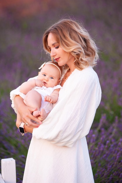 Madre feliz con una hija bonita con antecedentes de lavanda. Hermosa mujer y lindo bebé