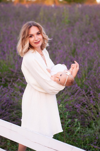 Madre feliz con una hija bonita con antecedentes de lavanda. Hermosa mujer y lindo bebé