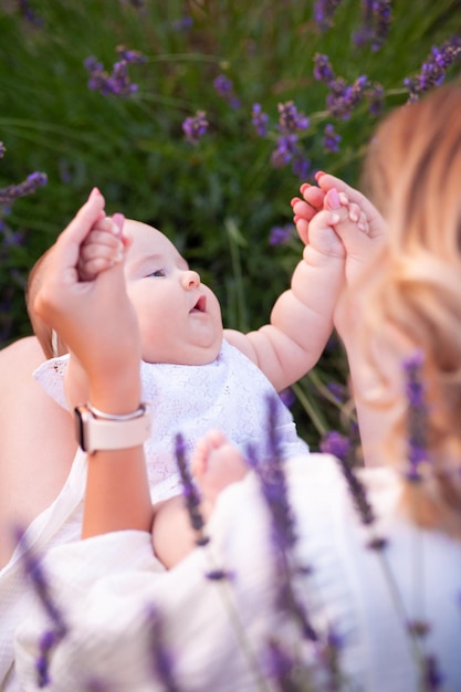 Madre feliz con una hija bonita con antecedentes de lavanda. Hermosa mujer y lindo bebé