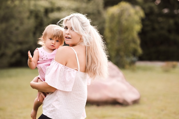 Madre feliz jugando con la niña en el parque al aire libre