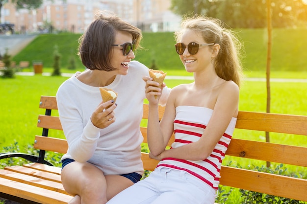 Madre feliz y linda hija adolescente en el parque de la ciudad