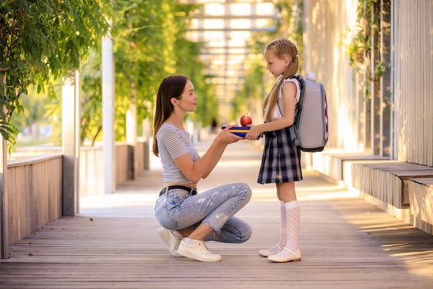 Madre feliz lleva a la colegiala a la escuela