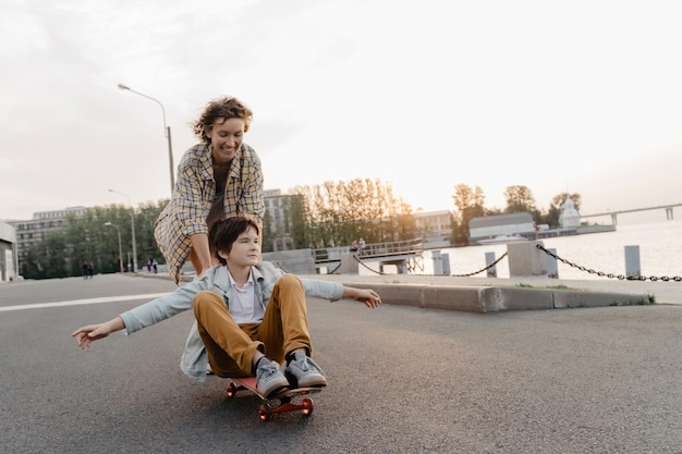 Madre feliz montando a su hijo en patineta