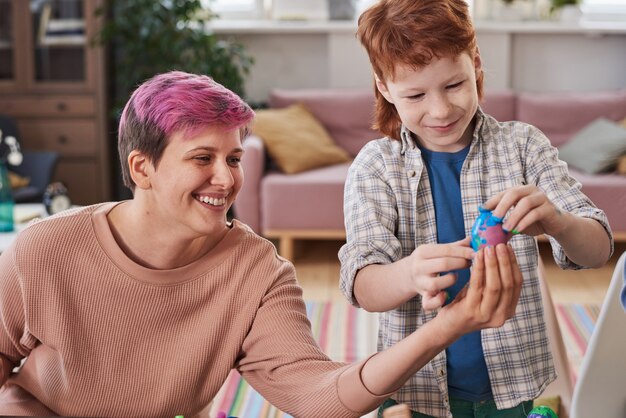 Madre feliz mostrando huevos de Pascua pintados a su hijo mientras celebran la Pascua