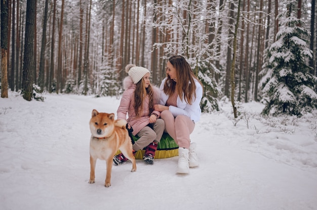 Madre feliz y niña linda en ropa de abrigo rosa caminando divirtiéndose paseos en tubo de nieve inflable