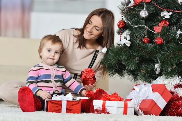 Madre feliz con un niño cerca de un árbol de Navidad. regalos de año nuevo