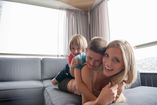 Madre feliz con niños divirtiéndose en el suelo en casa