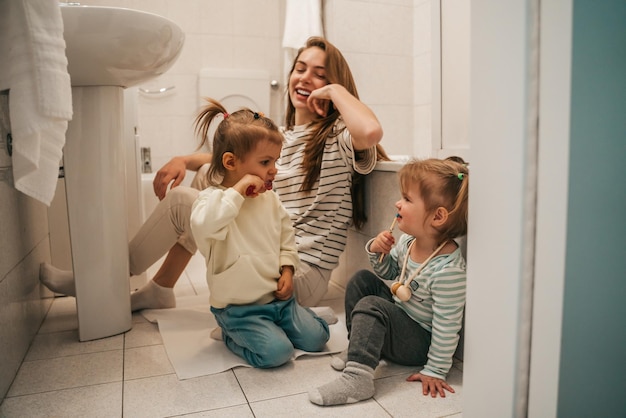 Madre feliz observando a sus hijos durante el procedimiento de cepillado de dientes