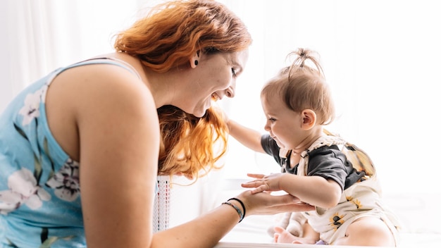 Foto madre feliz que apoya al bebé lindo