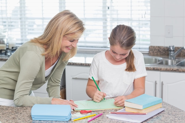 Madre feliz que ayuda a la hija que hace la tarea