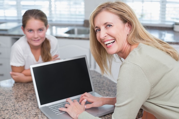 Madre feliz que usa la computadora portátil con su hija