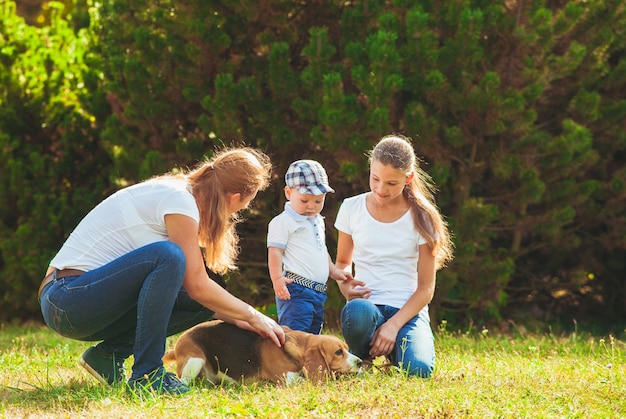 Madre feliz con su hija, hijo pequeño y perro beagle a pasear