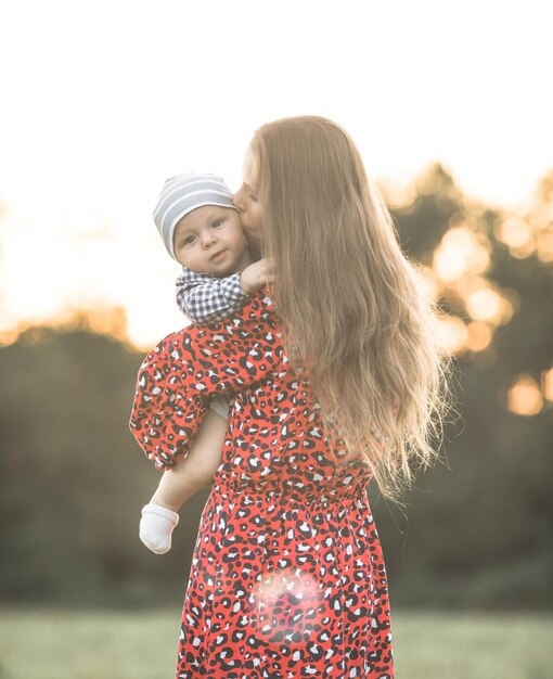 Madre feliz con su hijo disfrutando de la naturaleza en un día soleado Foto de una hermosa joven madre jugando y abrazando a su lindo hijo