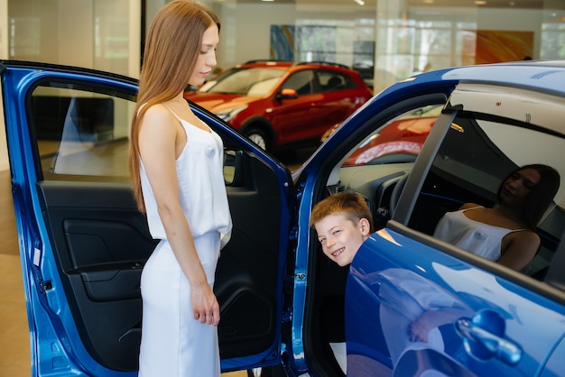 Una madre feliz con su hijo pequeño elige un automóvil nuevo en un concesionario de automóviles