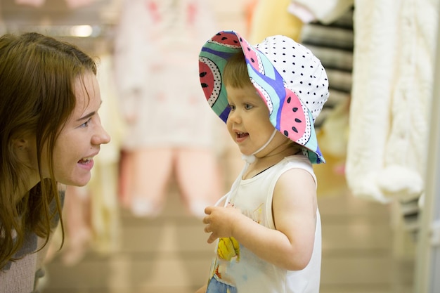 Madre feliz y su niña en el sombrero divirtiéndose durante las compras