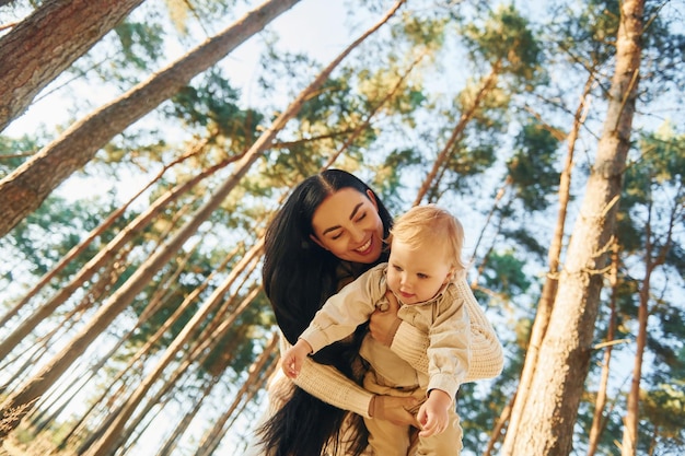 La madre feliz con su pequeña hija está en el bosque