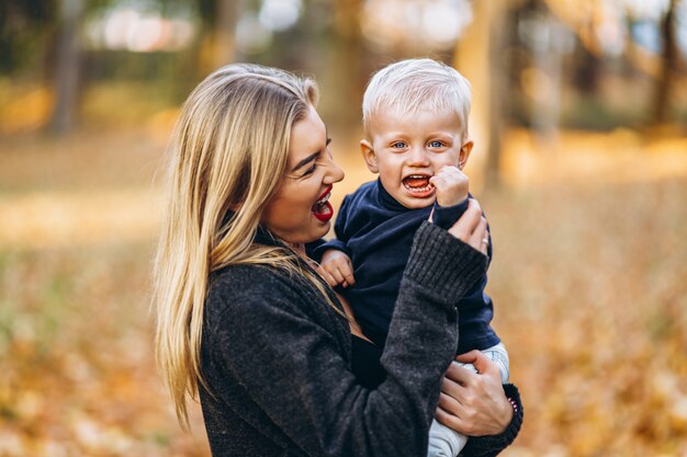 Madre feliz con su pequeño hijo se divierten en el parque de la ciudad