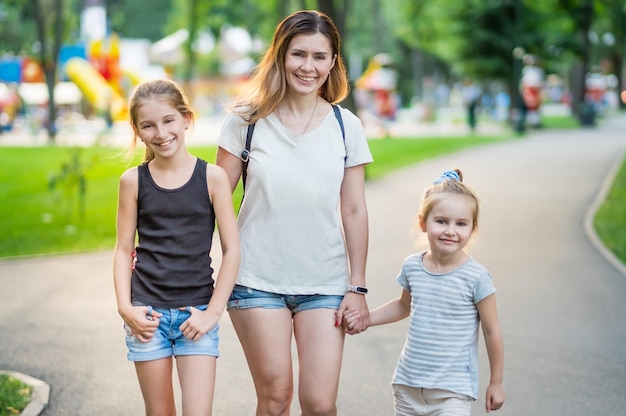 Madre feliz con sus lindas hijas al aire libre madre sonriente con hijas encantadoras caminando