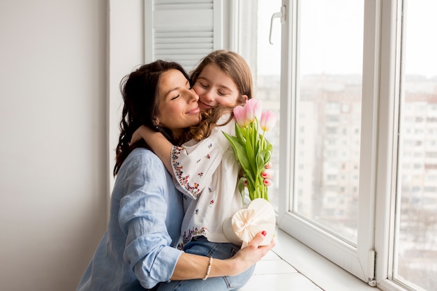 Foto madre con flores abrazando a hija