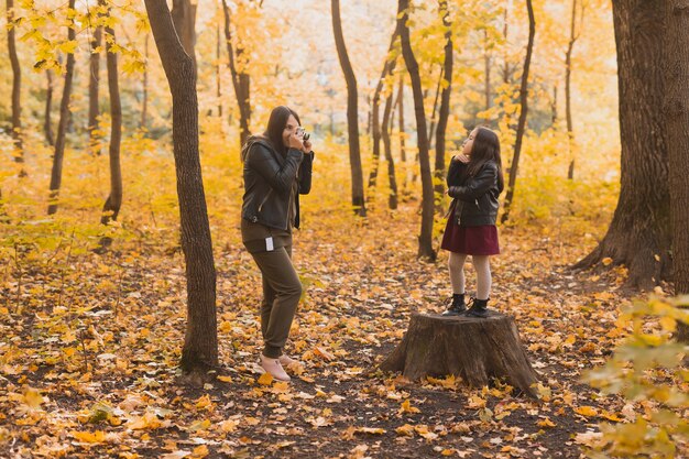 Madre fotógrafa toma fotografías de su hija en el parque en otoño, aficiones, arte fotográfico y