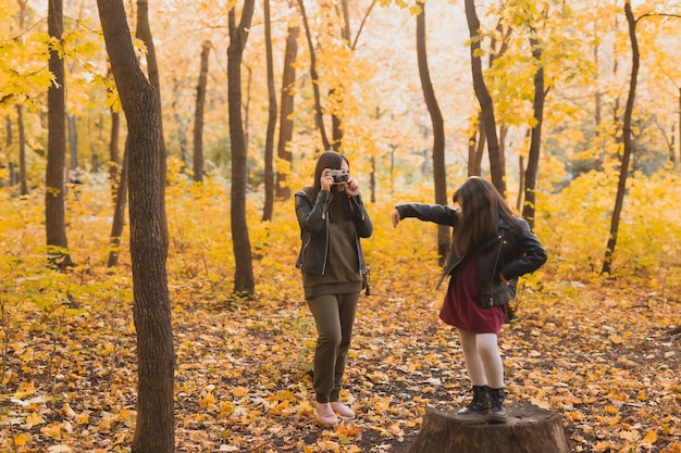 La madre fotógrafa toma fotos de su hija en el parque en otoño Aficiones, arte fotográfico y concepto de ocio