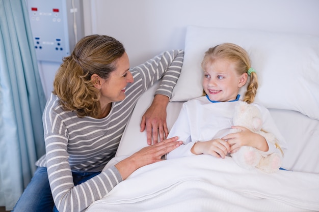 Madre hablando con hija en cama de hospital