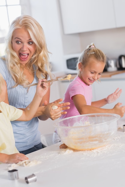 Madre haciendo una mueca mientras sus hijos cuidan la masa