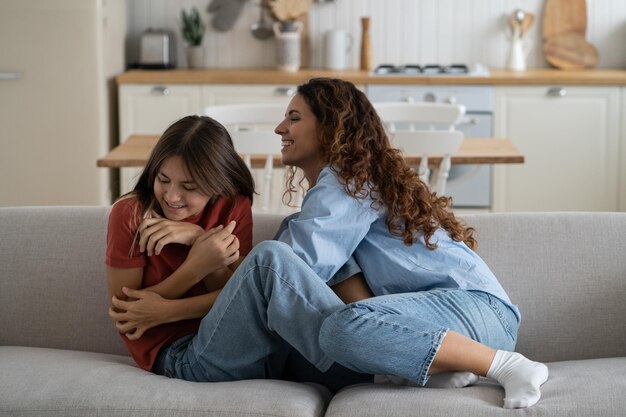 Foto madre y hija alegres divirtiéndose y riendo mientras pasan tiempo juntos en casa