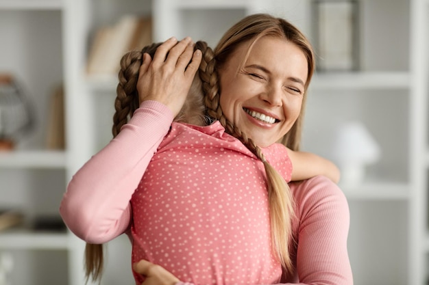 Foto madre hija ama a una mujer feliz abrazando a su pequeño hijo en casa