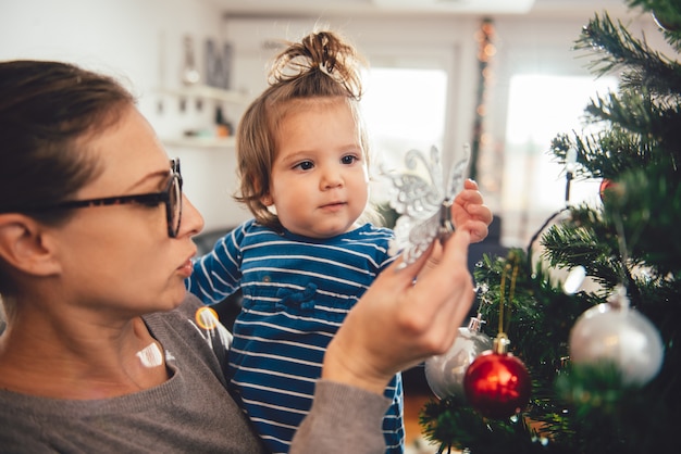 Madre con hija y árbol de Navidad de decoración