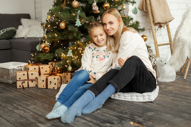 Madre con hija cerca del árbol de Navidad