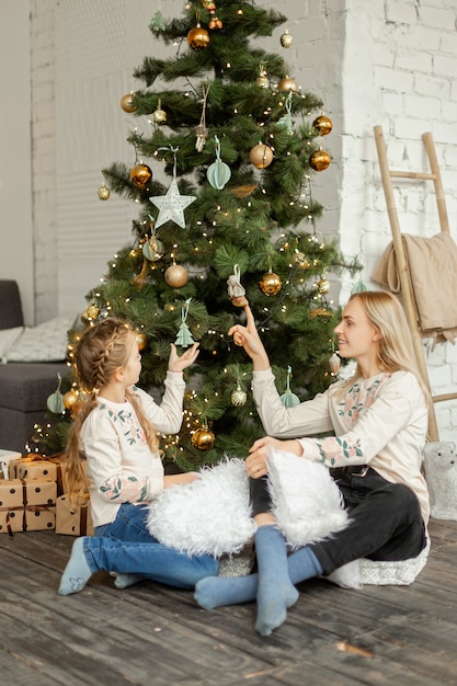 Madre con hija cerca del árbol de Navidad