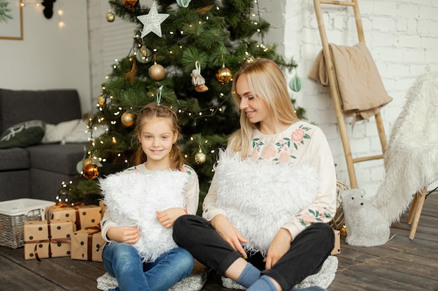 Madre con hija cerca del árbol de Navidad