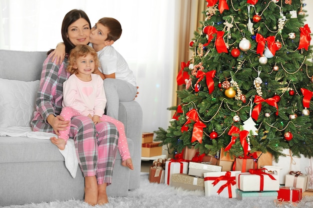 Madre con hija e hijo cerca del árbol de Navidad