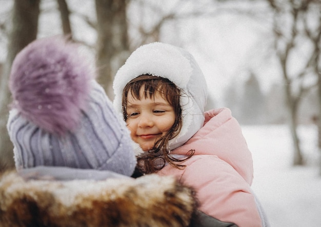 La madre y la hija de la familia feliz se divierten jugando en el paseo de invierno al aire libre. retrato de invierno de madre e hijo.