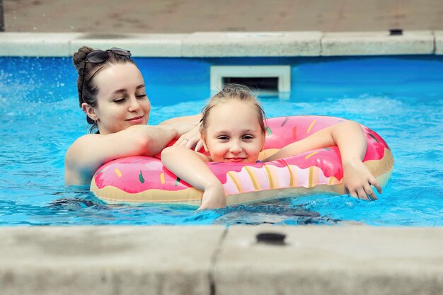 la madre y la hija de la familia nadan durante las vacaciones de verano en el agua de la piscina