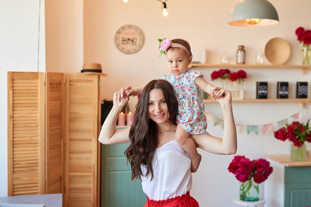 La madre y la hija de la familia con las peonías florecen en cocina en casa. Feliz madre e hija. Familia feliz.