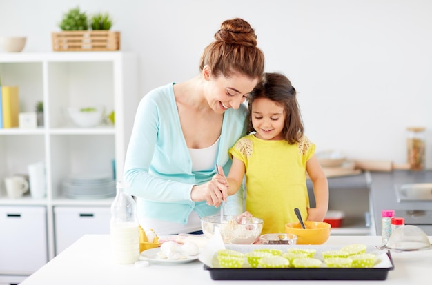 madre y hija felices horneando muffins en casa