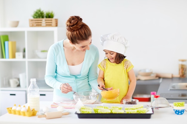 madre y hija felices horneando muffins en casa