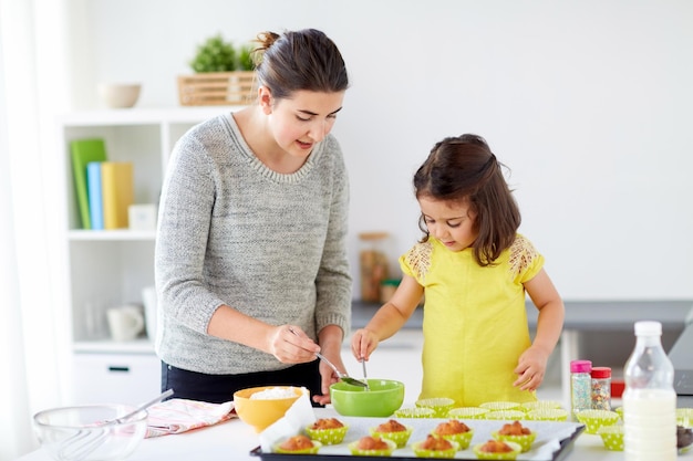 madre y hija felices horneando muffins en casa