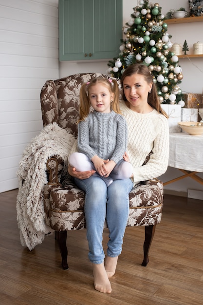 Madre con hija en el fondo de casa de Navidad