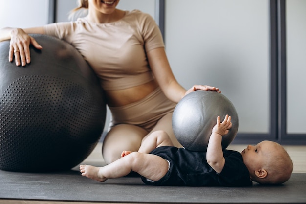 Madre con hija haciendo ejercicio con pelota de yoga