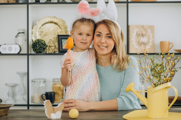 Madre con hija junto a la cocina con huevos de pascua