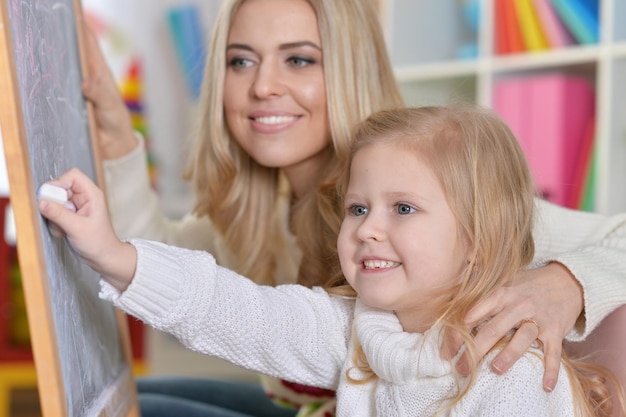 Madre con hija pequeña escribiendo en la pizarra