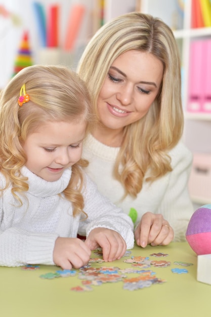 Madre con hija pequeña jugando con osito de peluche, escorando