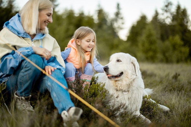 Madre con hija y perro sentada en la naturaleza